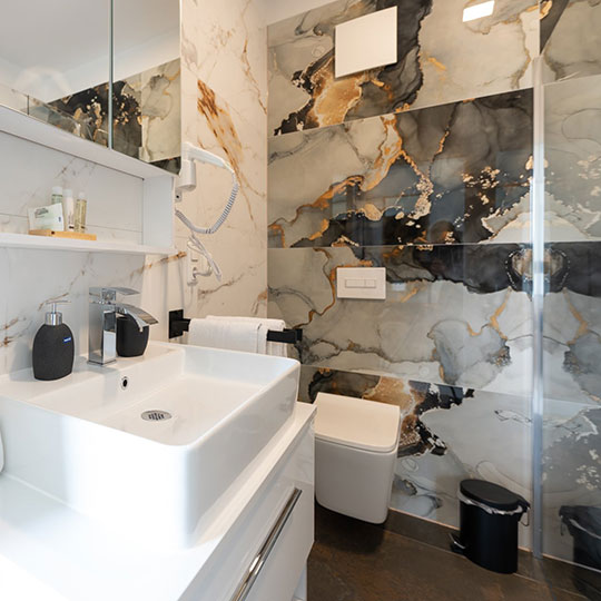 Modernes Badezimmer mit weißem Aufsatzbecken, Chromarmatur, Haartrockner, wandhängendem WC und expressiv gemusterten Marmorfliesen