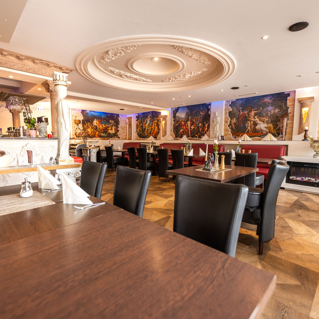 Elegantes Restaurant mit schwarzen Stühlen, roten Sitzbänken, antiken Wandgemälden und dekorativer Deckenrosette